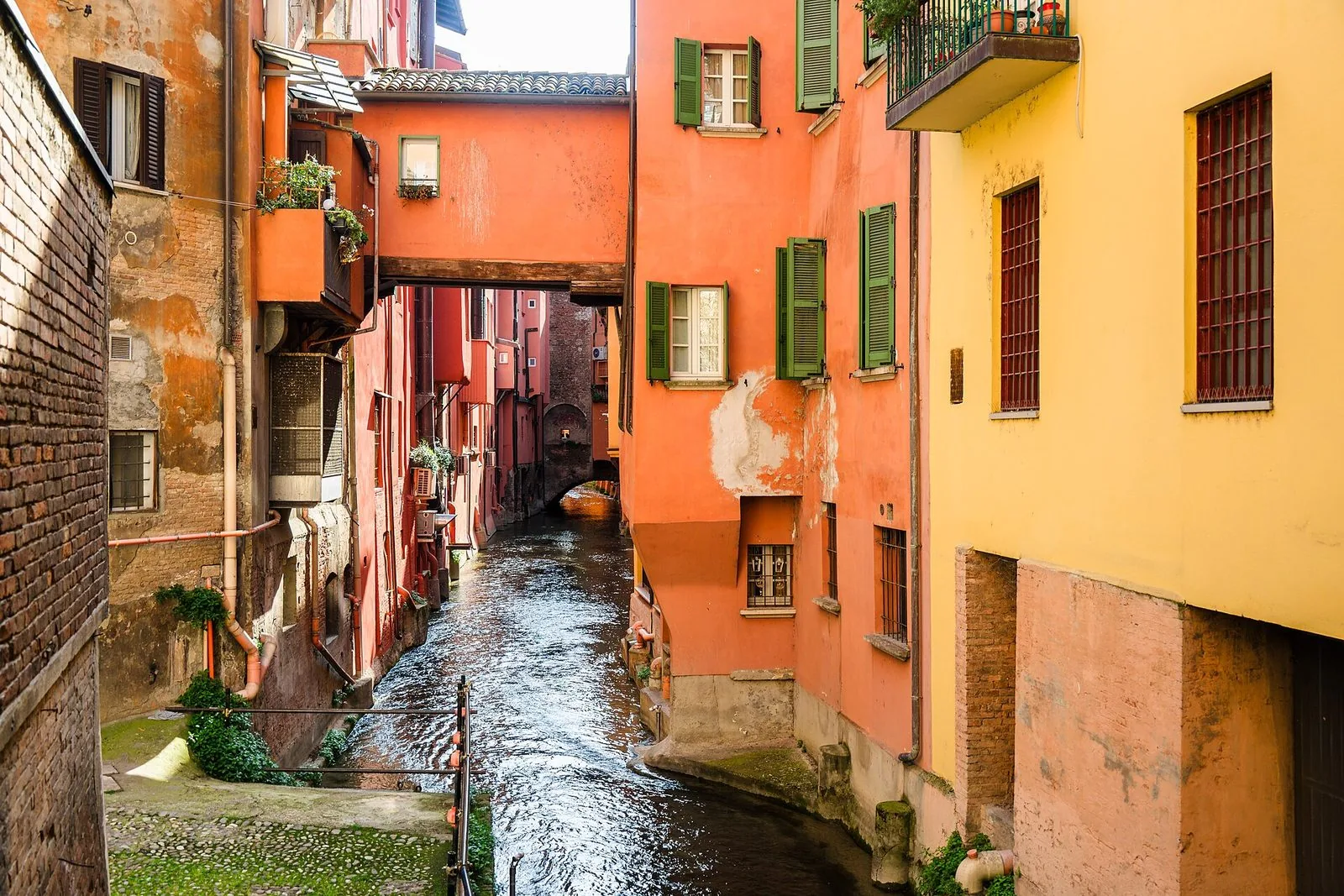 Il Canale delle Moline che scorre tra case color arancio e giallo con persiane verdi, attraversato da un passaggio coperto che unisce due edifici sopra l'acqua