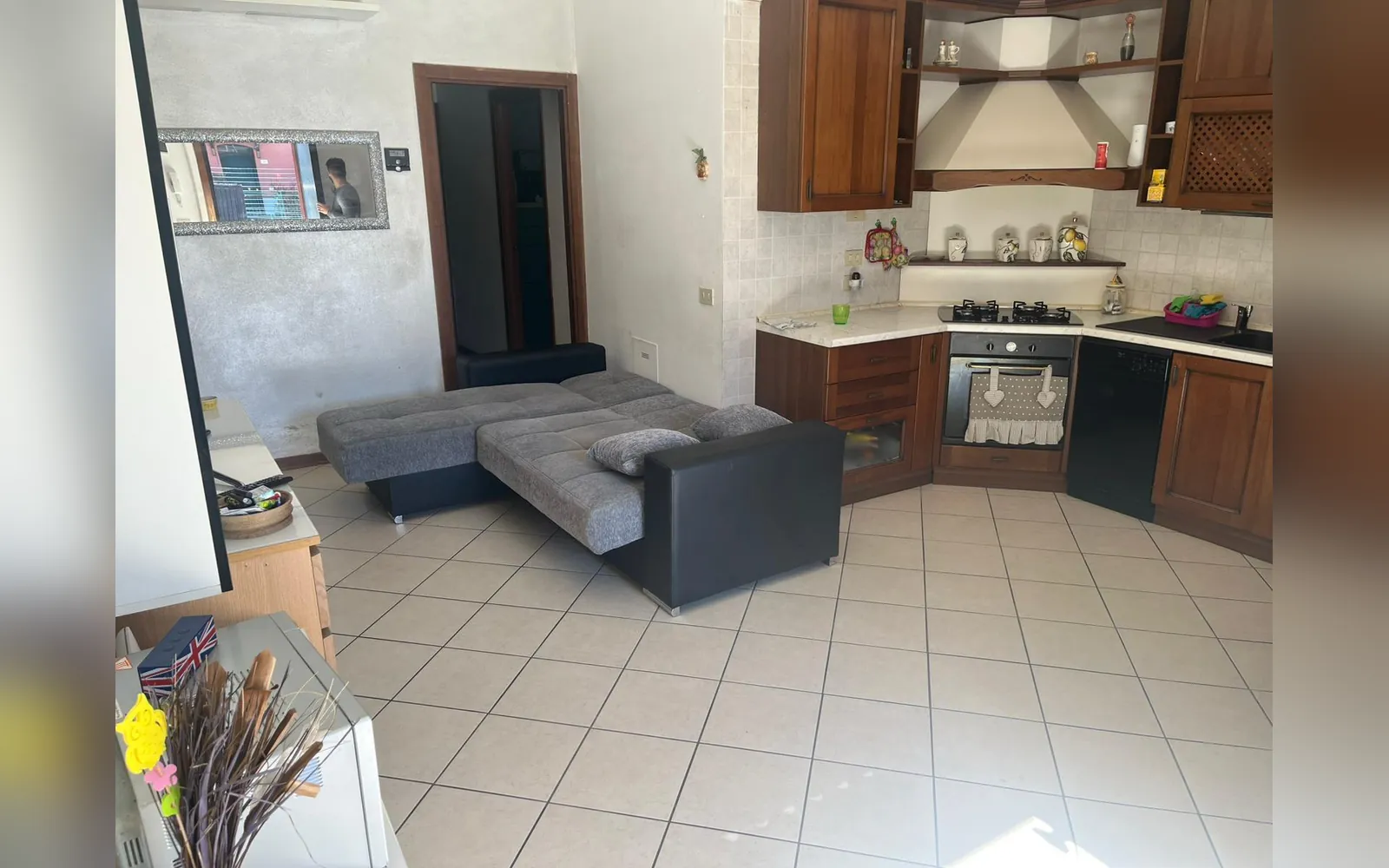 La grande sala con il divano letto aperto e l’angolo cucina in legno