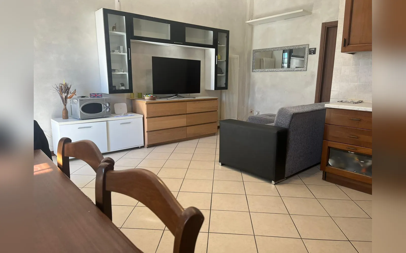 La sala con il mobile TV, il divano e il tavolo in legno